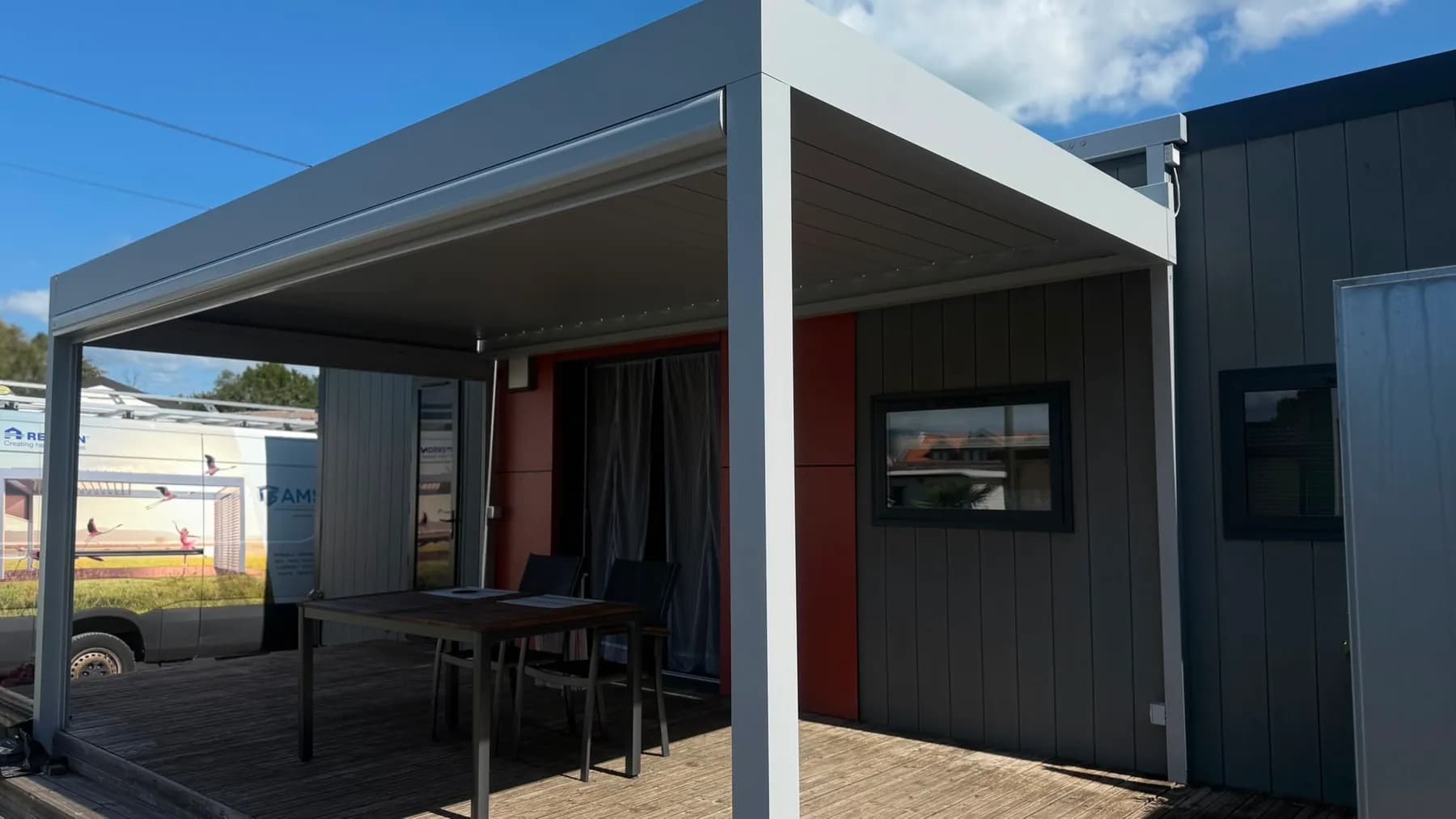 Pergola bioclimatique à structure claire sur une terrasse en bois à Estavayer
