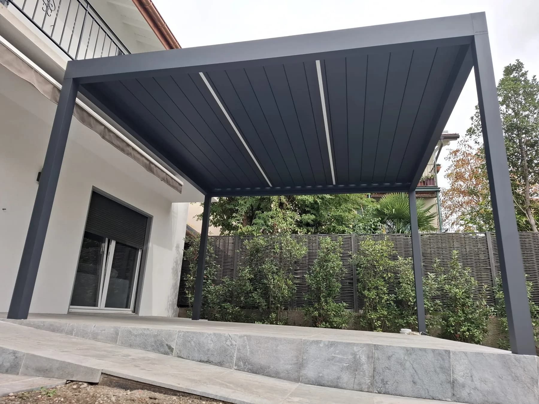 Sous la pergola anthracite de Nyon, deux bandeaux LED traversent les lames